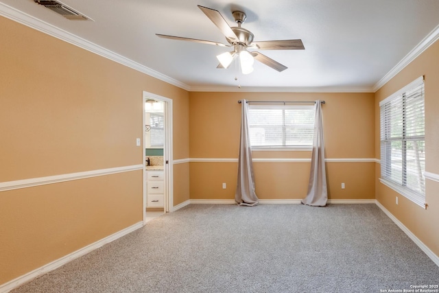 carpeted empty room featuring baseboards, visible vents, ceiling fan, and crown molding