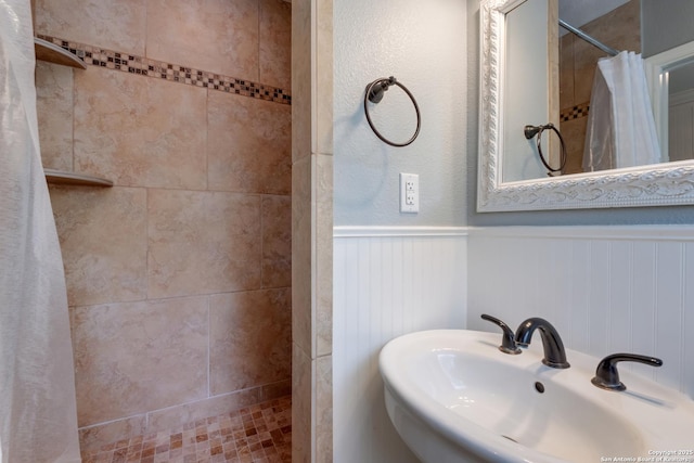 bathroom featuring wainscoting, a sink, and tiled shower