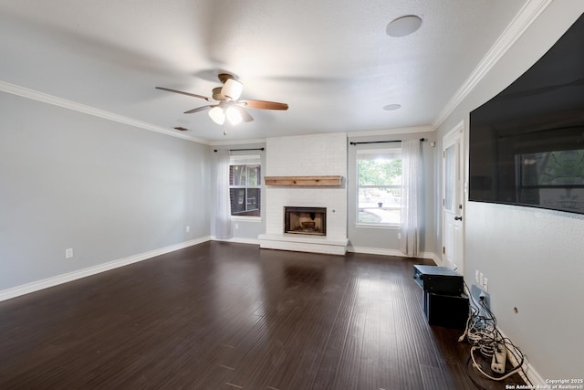 unfurnished living room with crown molding, a brick fireplace, a ceiling fan, and dark wood-style floors