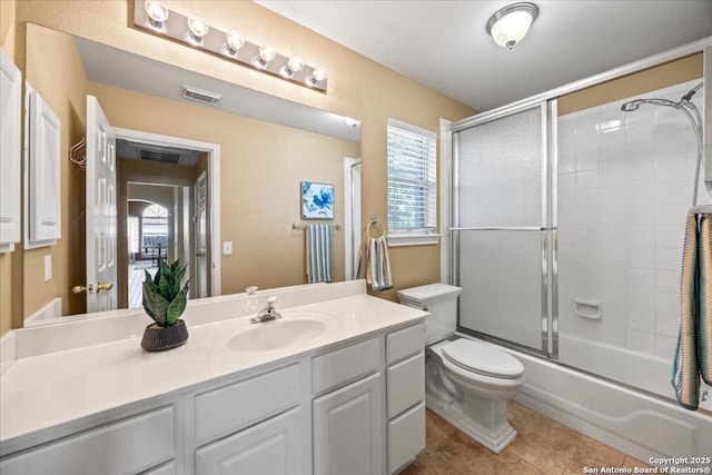 full bath featuring visible vents, enclosed tub / shower combo, vanity, and toilet