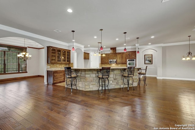 kitchen with decorative backsplash, baseboards, appliances with stainless steel finishes, and a chandelier
