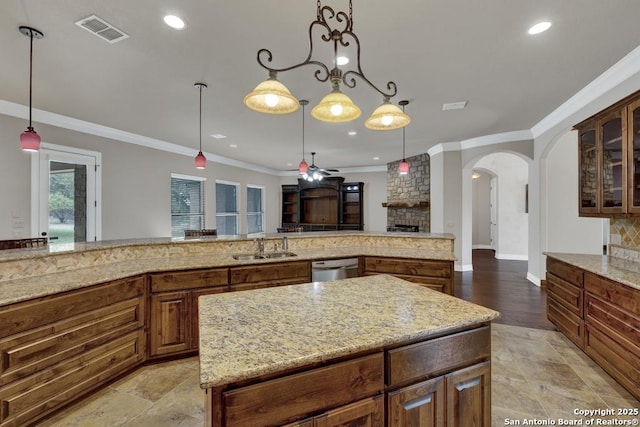 kitchen with visible vents, a sink, arched walkways, light stone countertops, and crown molding