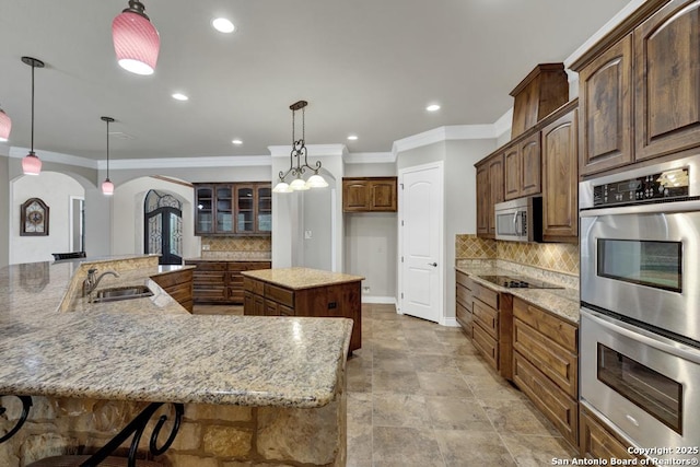 kitchen with crown molding, a sink, a spacious island, arched walkways, and appliances with stainless steel finishes