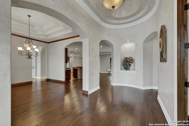 interior space featuring baseboards, crown molding, a tray ceiling, and dark wood-style floors