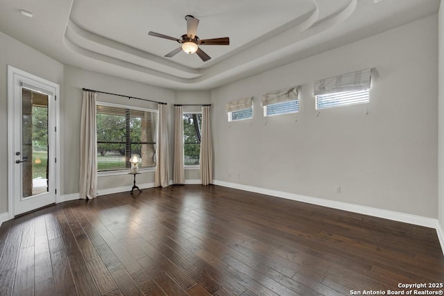 spare room featuring baseboards, a ceiling fan, a tray ceiling, and hardwood / wood-style floors