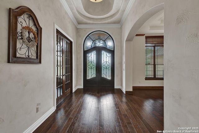 entrance foyer featuring french doors, arched walkways, a raised ceiling, and wood-type flooring