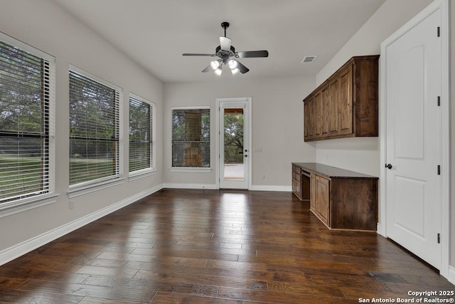 unfurnished dining area with ceiling fan, baseboards, dark wood-style flooring, and visible vents