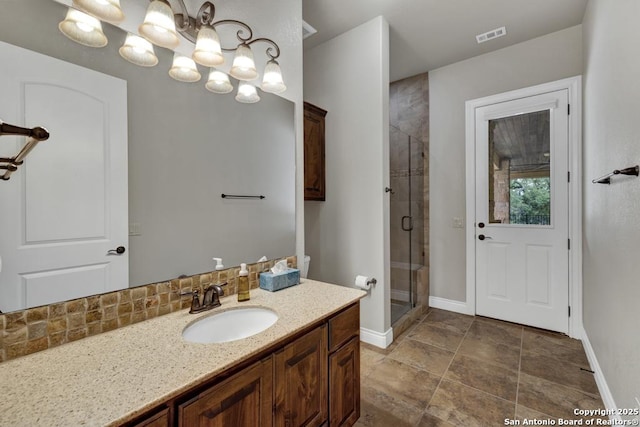 full bath with a stall shower, visible vents, baseboards, an inviting chandelier, and vanity