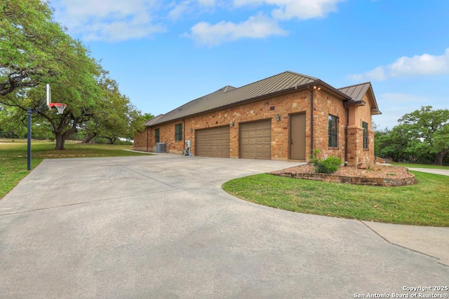 view of property exterior featuring an attached garage, a standing seam roof, a lawn, and driveway