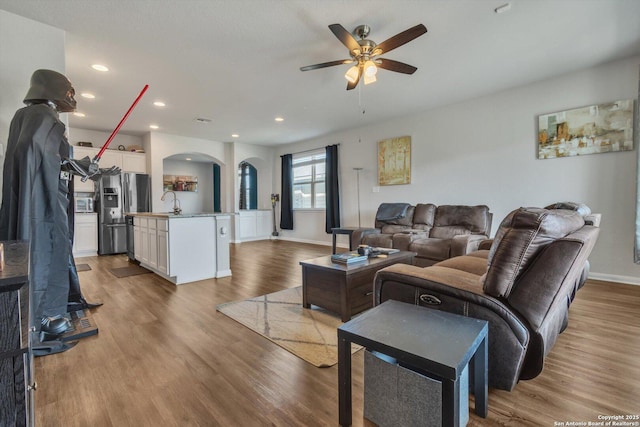 living room featuring recessed lighting, wood finished floors, arched walkways, baseboards, and ceiling fan