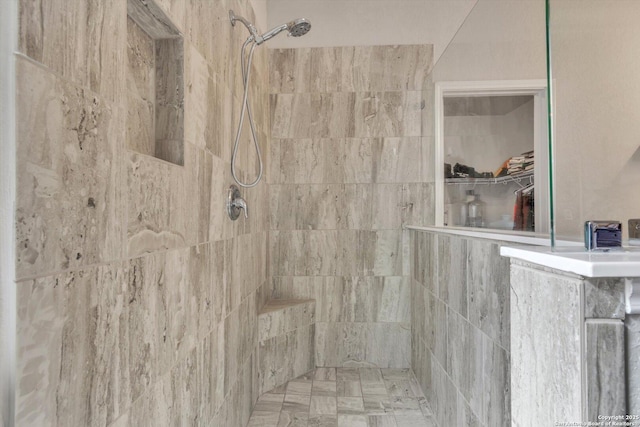 bathroom with a walk in closet and a tile shower