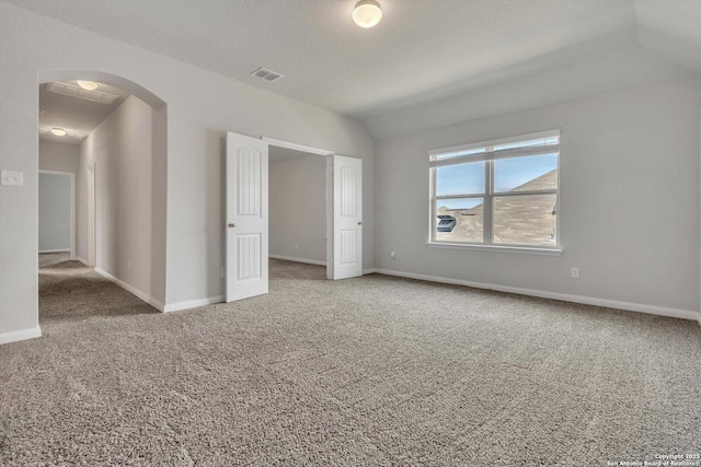 unfurnished bedroom featuring carpet flooring, arched walkways, baseboards, visible vents, and lofted ceiling