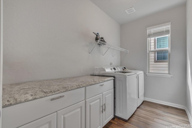 laundry room featuring washing machine and dryer, baseboards, wood finished floors, and visible vents