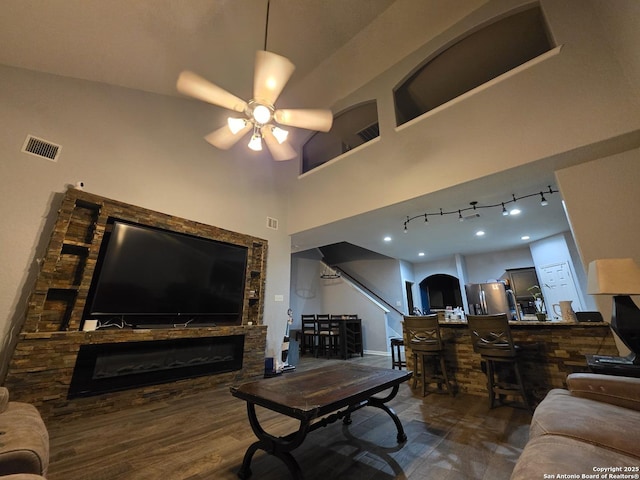 12031 Mill Love, San Antonio, TX 78254 - living area with a stone fireplace, a ceiling fan, a towering ceiling, wood finished floors, and a bar