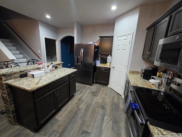 12031 Mill Love, San Antonio, TX 78254 - kitchen with appliances with stainless steel finishes, light wood-type flooring, a textured wall, light stone countertops, and a kitchen island