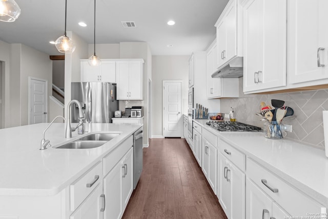 kitchen featuring under cabinet range hood, stainless steel appliances, light countertops, a sink, and dark wood-style flooring