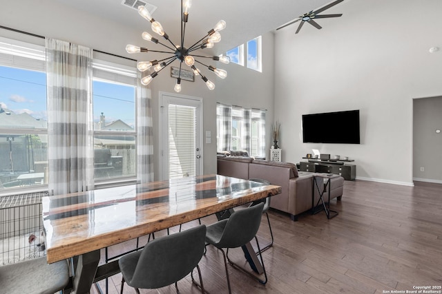 dining area featuring visible vents, baseboards, a notable chandelier, wood finished floors, and a high ceiling