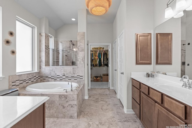 full bath featuring a walk in closet, a garden tub, vanity, and a stall shower