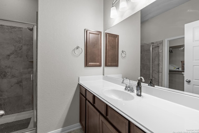 full bathroom featuring baseboards, vanity, a textured wall, and a stall shower