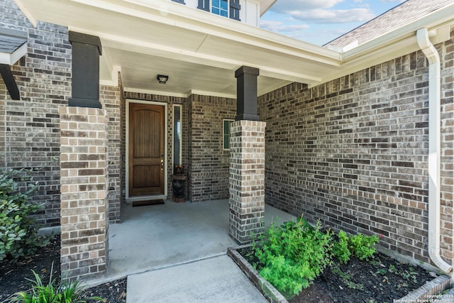 entrance to property with covered porch and brick siding