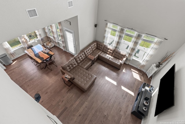 living area with wood finished floors, visible vents, and a towering ceiling