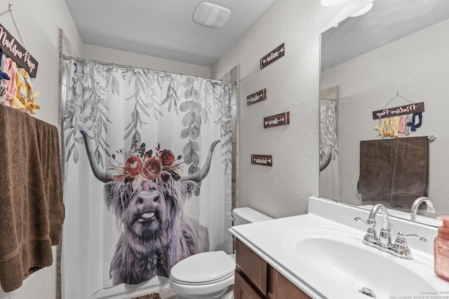 full bath featuring a shower with curtain, a textured wall, vanity, and toilet