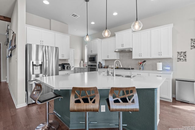 kitchen with stainless steel appliances, visible vents, a sink, and dark wood-type flooring
