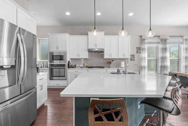 kitchen with a kitchen breakfast bar, stainless steel appliances, light countertops, a sink, and tasteful backsplash