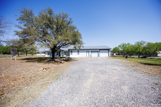 ranch-style house featuring gravel driveway and a garage