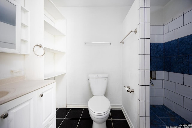 bathroom featuring toilet, tiled shower, baseboards, tile patterned flooring, and vanity
