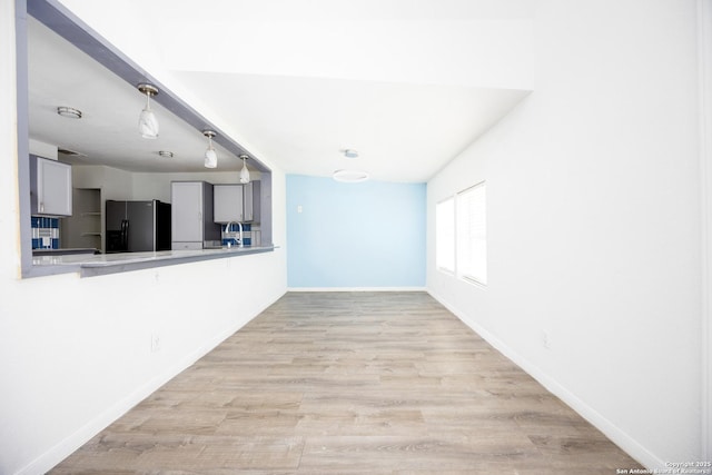 interior space with baseboards, a sink, and light wood-type flooring