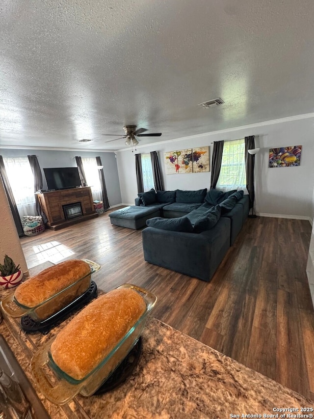 living room featuring wood finished floors, ceiling fan, a textured ceiling, and visible vents