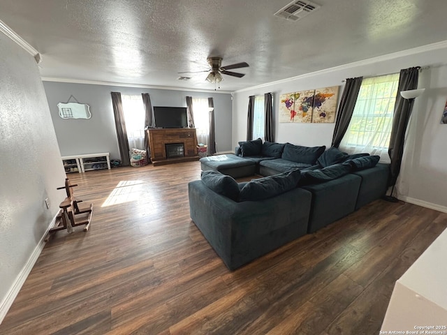 living room with crown molding, plenty of natural light, a ceiling fan, and visible vents