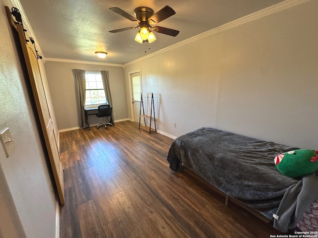 bedroom featuring ceiling fan, a barn door, baseboards, dark wood-style floors, and ornamental molding