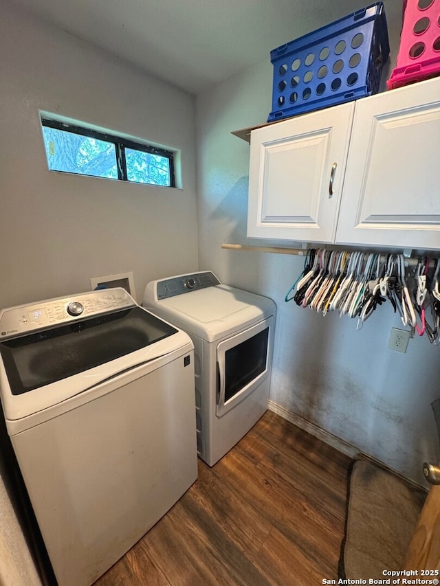 laundry room featuring washing machine and clothes dryer, dark wood-type flooring, and cabinet space
