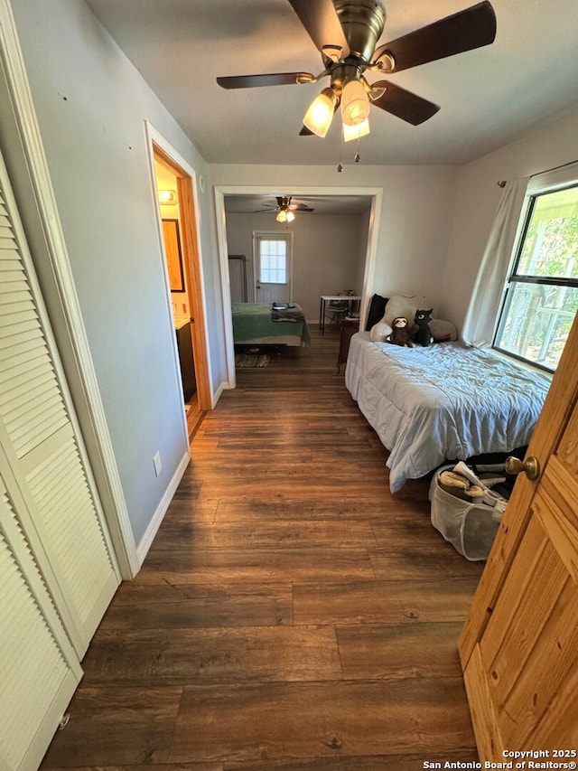 bedroom featuring baseboards, a ceiling fan, dark wood-style flooring, and multiple windows