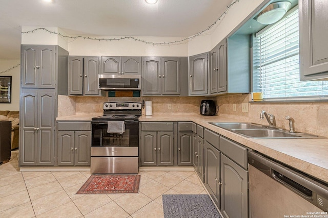 324 Craddock, San Marcos, TX 78666 - kitchen featuring a sink, decorative backsplash, stainless steel appliances, light countertops, and gray cabinetry