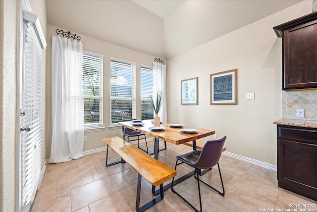 dining room with vaulted ceiling, a wealth of natural light, and baseboards