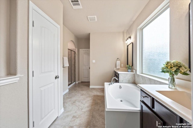 bathroom featuring a shower stall, a garden tub, vanity, and visible vents