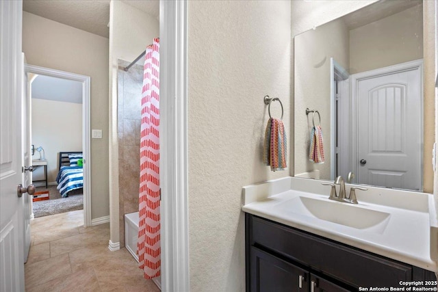 ensuite bathroom featuring tile patterned floors, a textured wall, vanity, shower / tub combo, and ensuite bathroom
