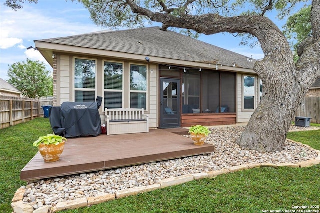 back of house with roof with shingles, fence, a deck, a yard, and a sunroom