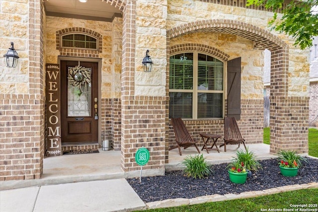 property entrance featuring brick siding, a porch, and stone siding
