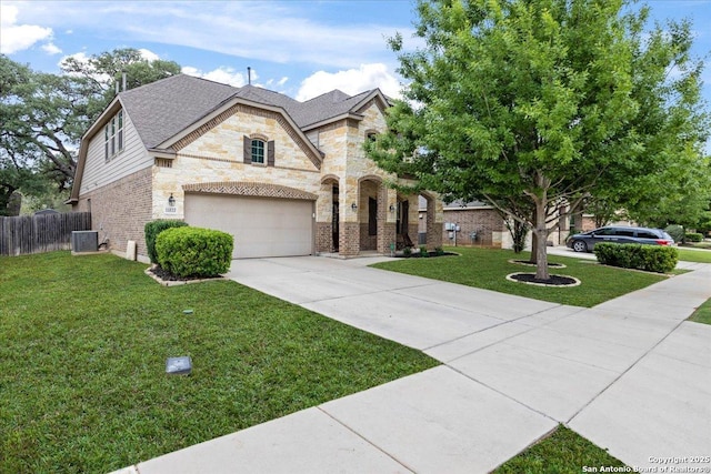 french country style house with a front lawn, central AC unit, driveway, stone siding, and fence