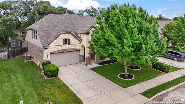 view of front of house with a front lawn, driveway, stone siding, fence, and a garage