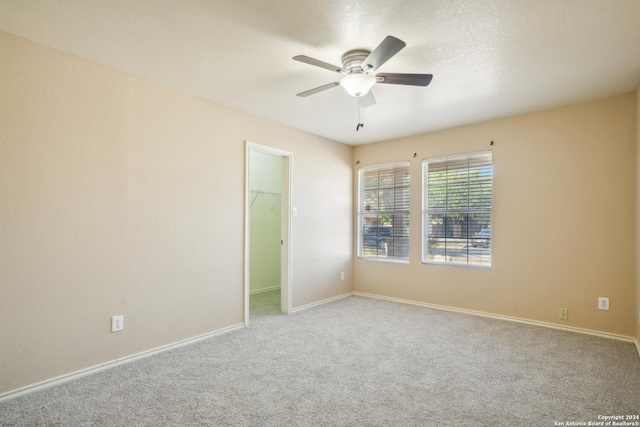 carpeted spare room with a ceiling fan and baseboards