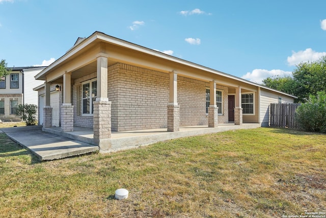 view of front of house featuring fence, covered porch, a front yard, and brick siding