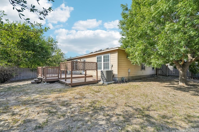 rear view of house with central AC unit, a wooden deck, and a fenced backyard