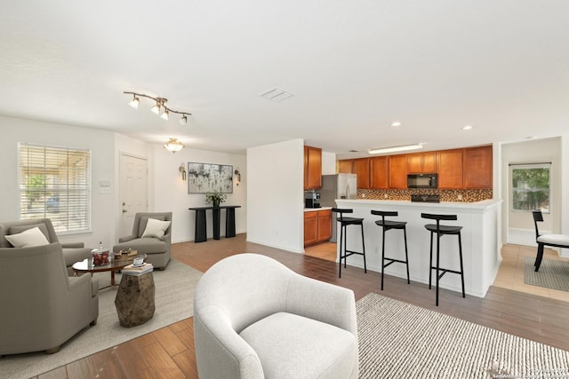 living area featuring light wood-style floors, plenty of natural light, recessed lighting, and baseboards
