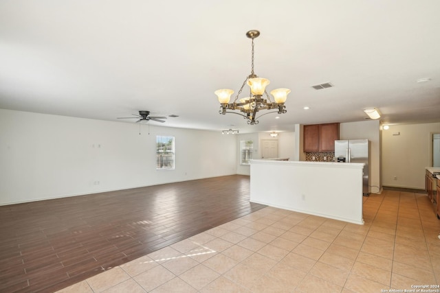 interior space featuring baseboards, visible vents, light tile patterned floors, and ceiling fan with notable chandelier