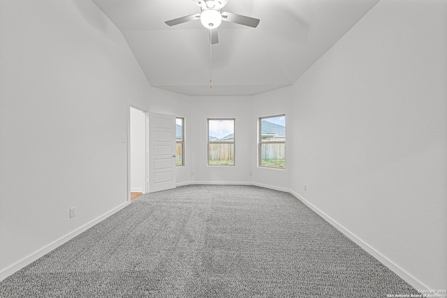empty room featuring carpet flooring, ceiling fan, vaulted ceiling, and baseboards
